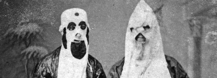 Two masked men in KKK costumes